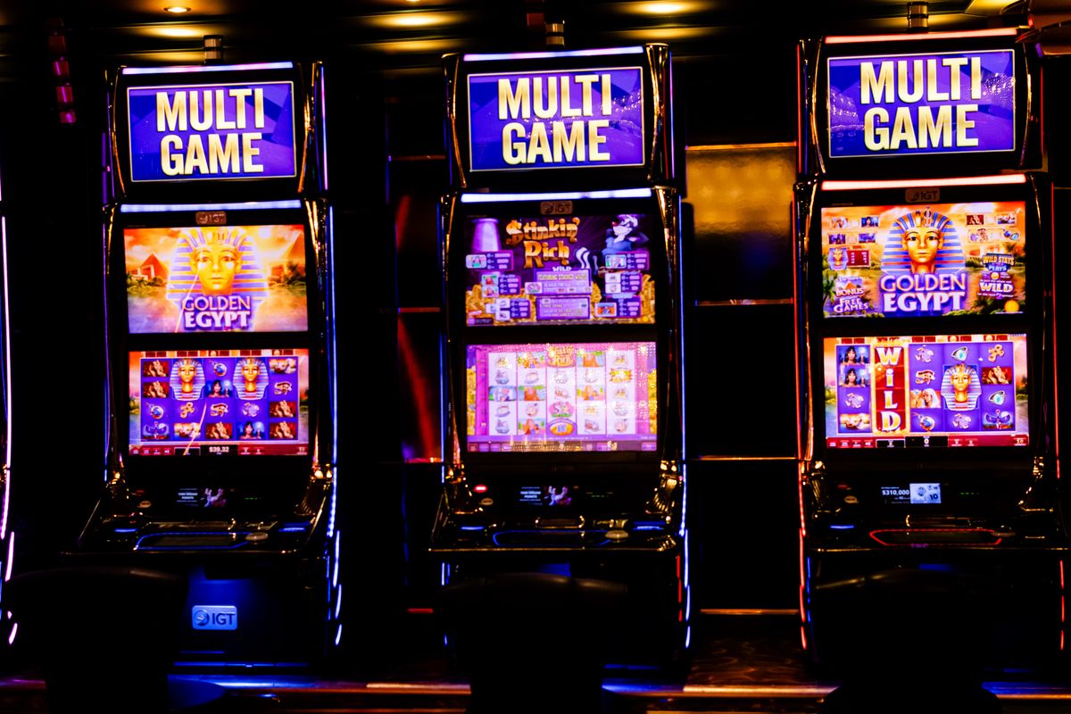 Tiga mesin slot berlampu di kasino malam hari