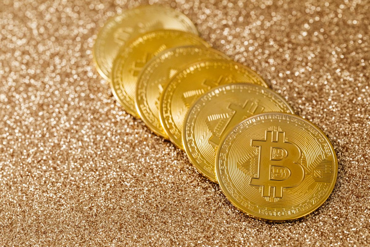 Tumpukan koin Bitcoin emas di latar berkilau
