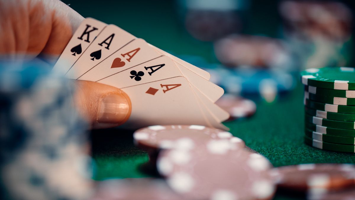 Tangan poker memegang empat kartu as dengan chip berwarna